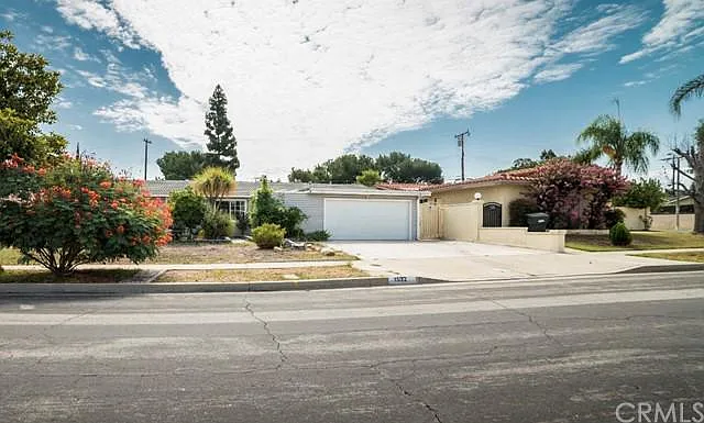 Suburban house with two-car garage, surrounded by trees.